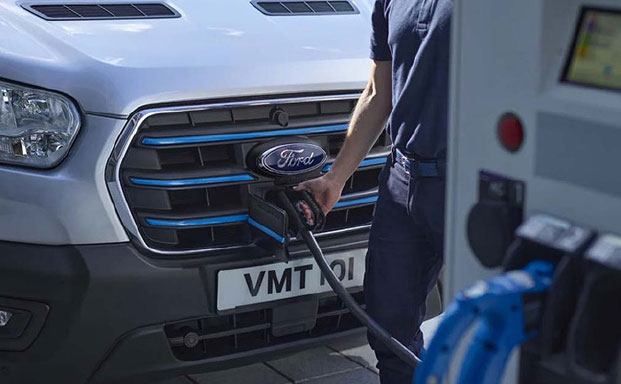 Närbilbild på en silver färgad Ford E-Transit snett fram stillastående som står på laddning